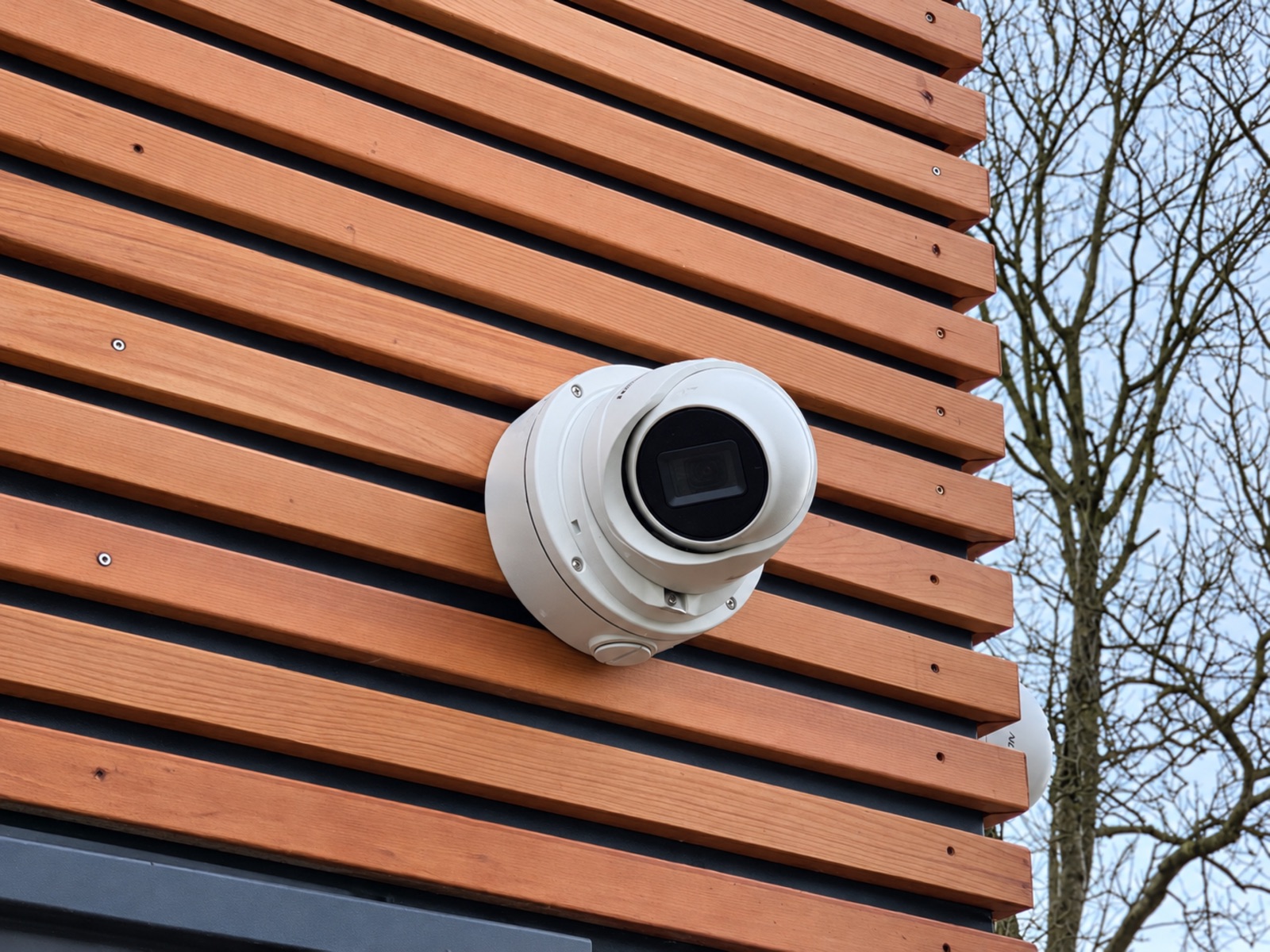 White CCTV turret camera installed on horizontal timber cladding