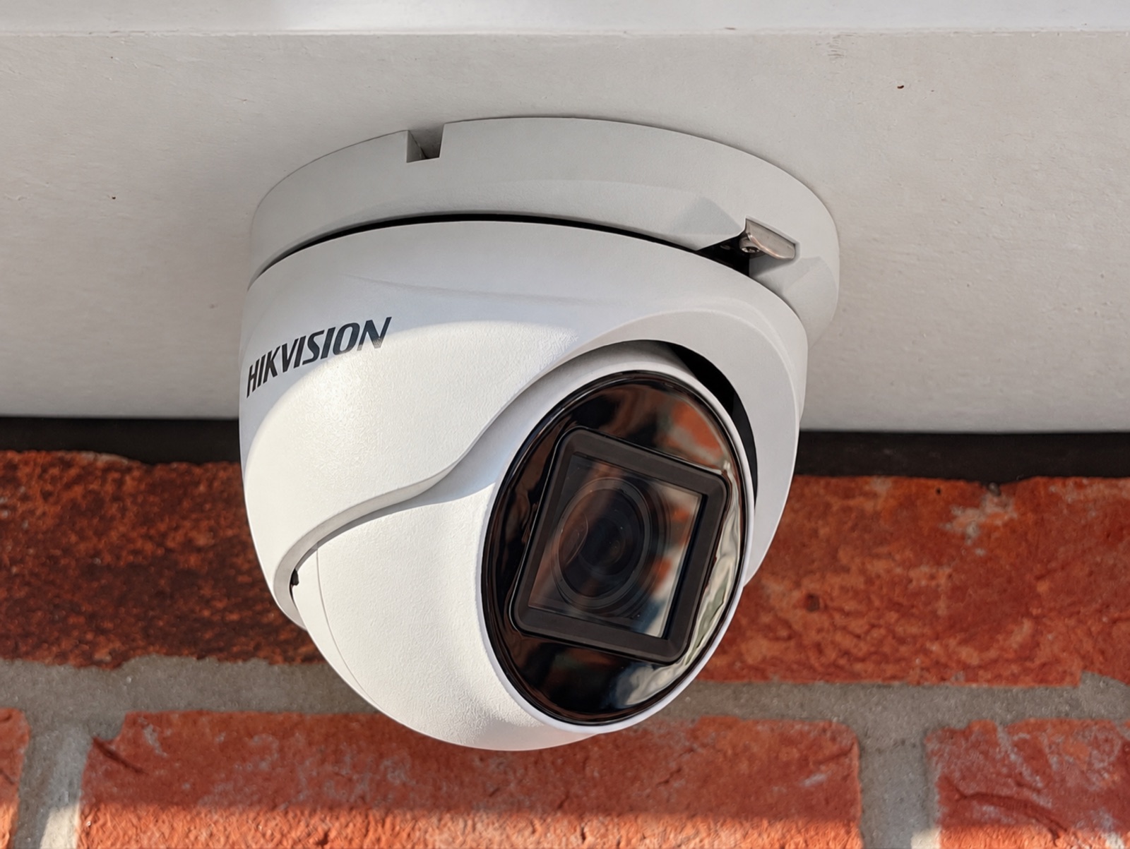 Hikvision CCTV camera fitted beneath the eaves of a brick building